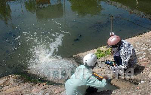 Cán bộ ngành môi trường đang kiểm tra lưu lượng nước và mức độ ô nhiễm từ một miệng cống nước thải đổ ra sông khu vực Cầu Giấy (Hà Nội). Ảnh Trọng Đạt/TTXVN